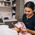 Cosmetologist applying mask on a face of client in a beauty salon